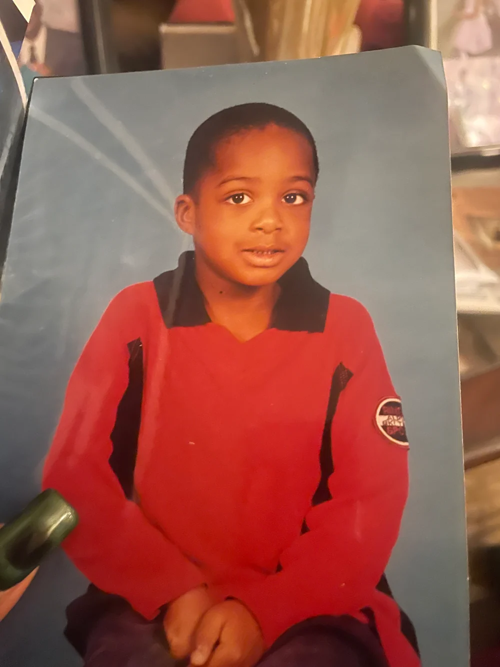A printed portrait of a child in a red shirt against a blue background