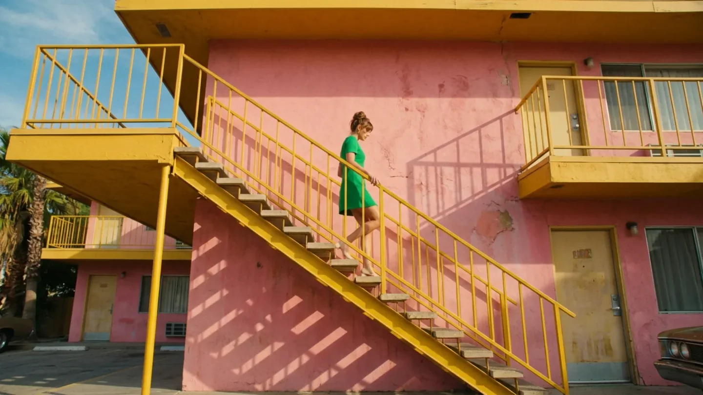 Official Nano Banana 2.1 example of a woman in a green dress on yellow stairs outside a pink motel